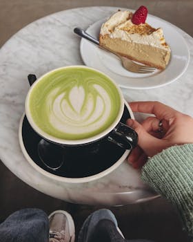 Enjoy a relaxing moment with a matcha latte and cake at a cozy cafe table.